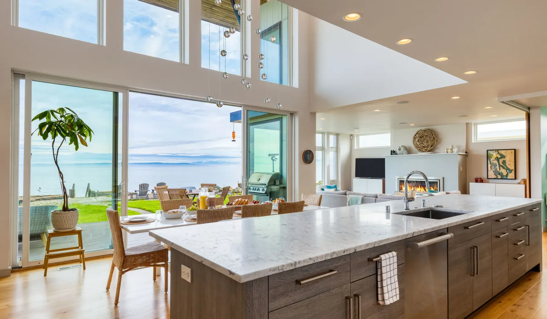 A bright open-plan kitchen and living area overlooks the water through large windows.