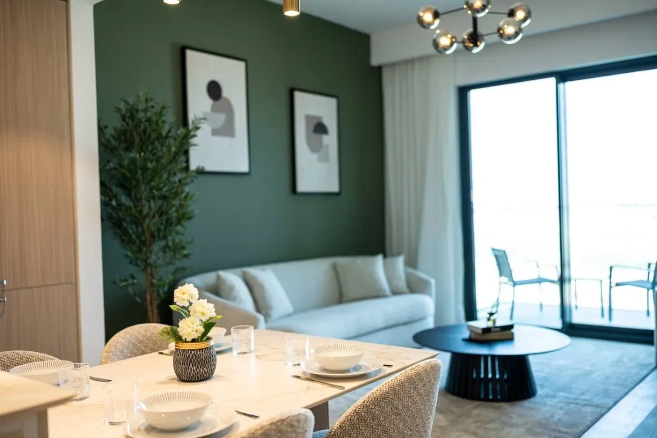 A dining and living area with a table, seating, and large windows.