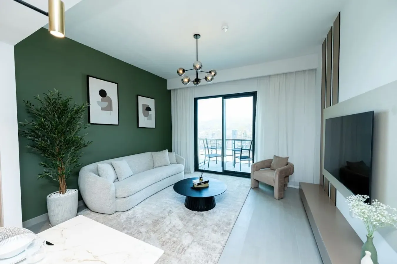 A modern living room with a light sofa, coffee table, and glass doors to a balcony.