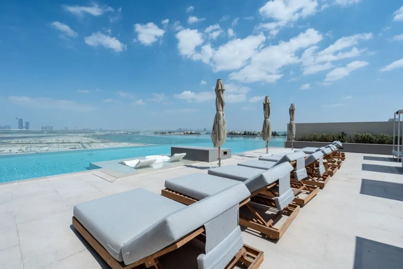 A sun deck with cushioned loungers beside a swimming pool.