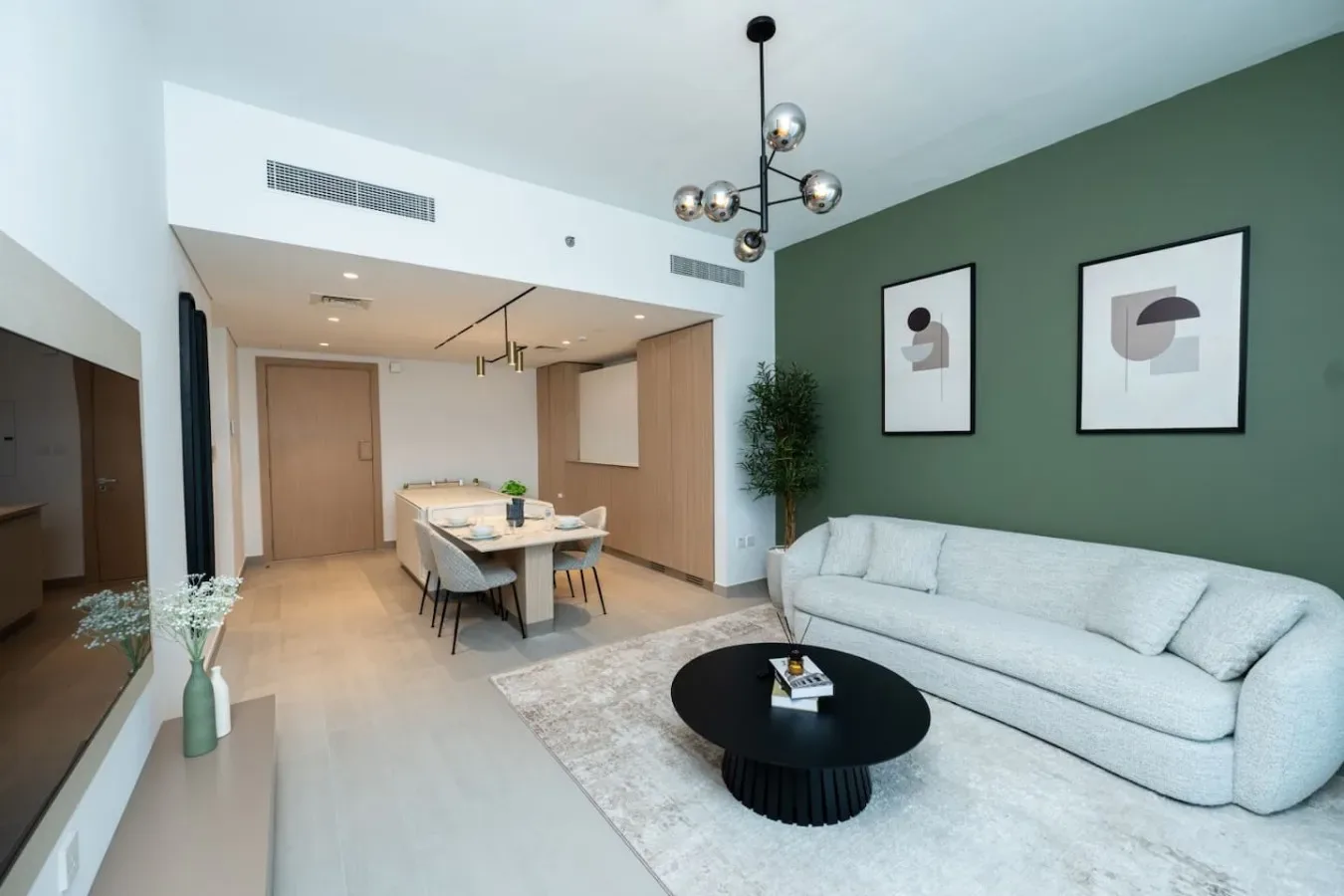 A modern living and dining area with a pale sofa and a round coffee table.