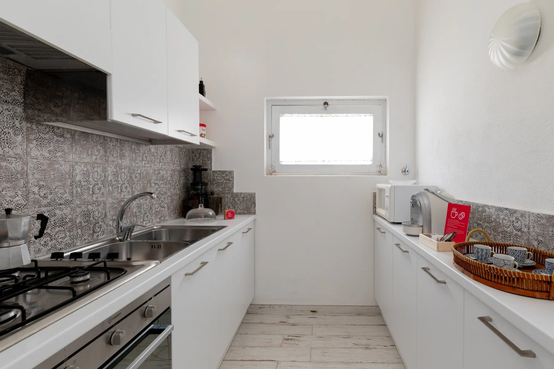 A bright kitchen with white cabinets, counters, and a window.