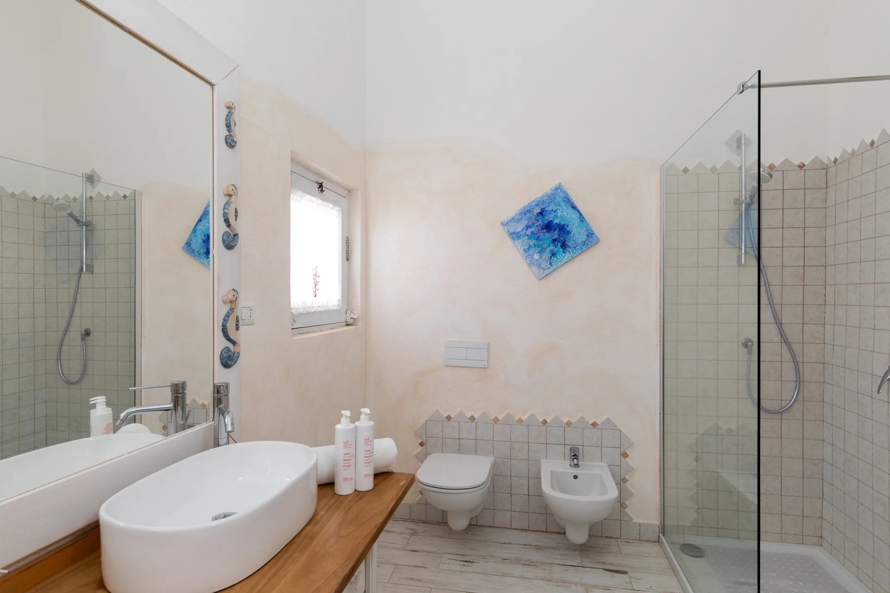 A bright bathroom with a sink, toilet, bidet, and glass shower.