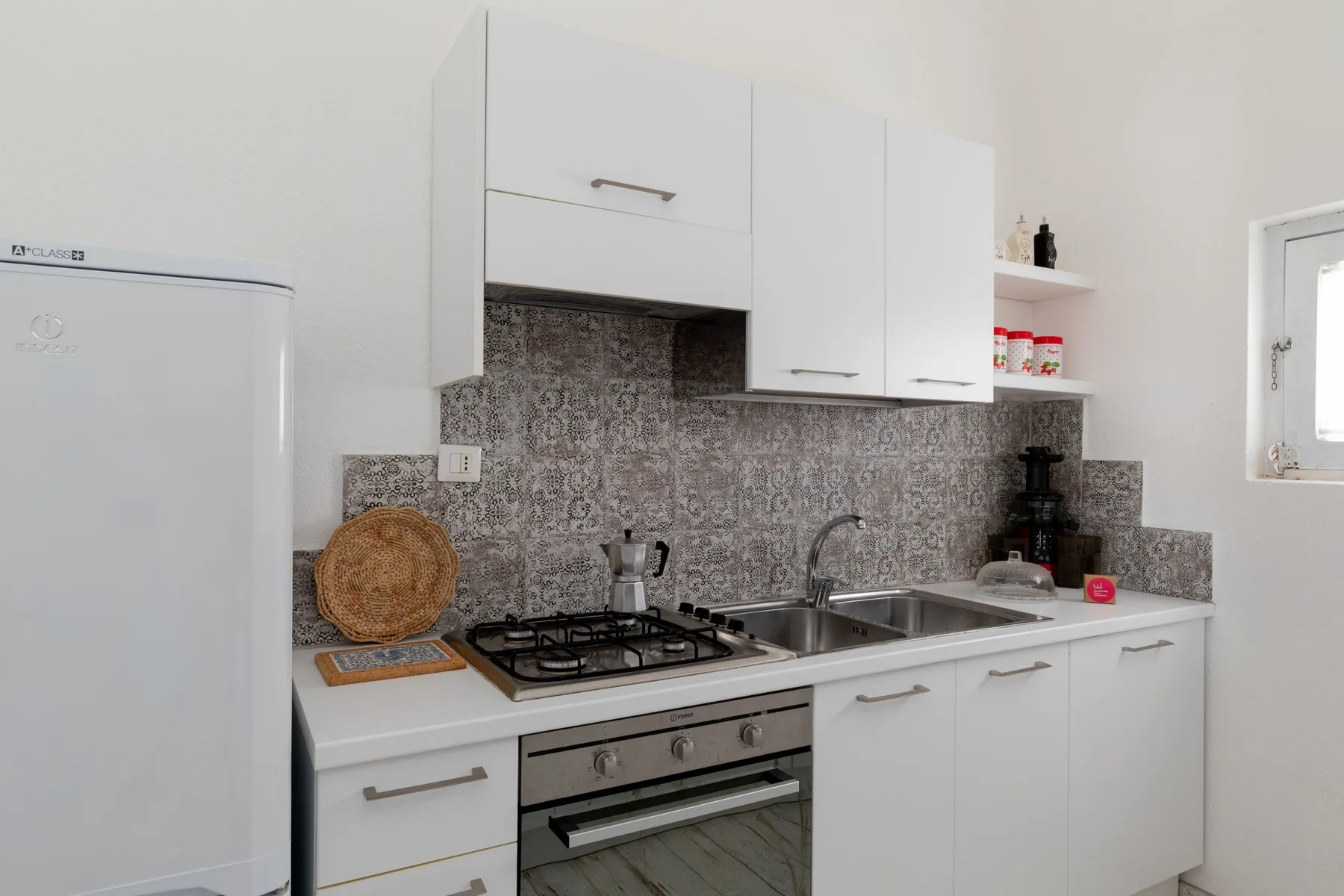 A bright kitchen with white cabinets, a gas cooktop, and a sink.