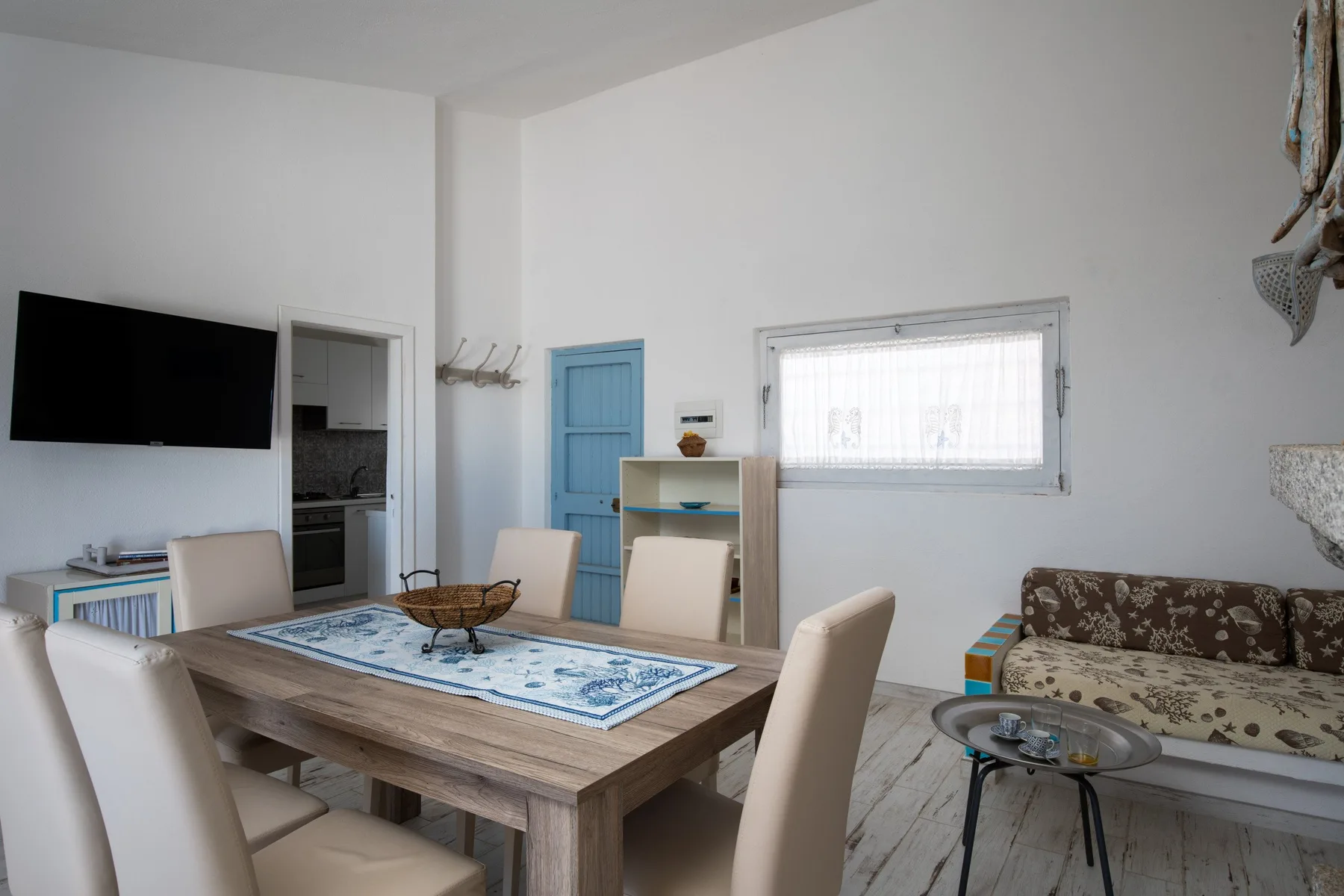 A dining and living area with a wooden table, blue door, and seating.