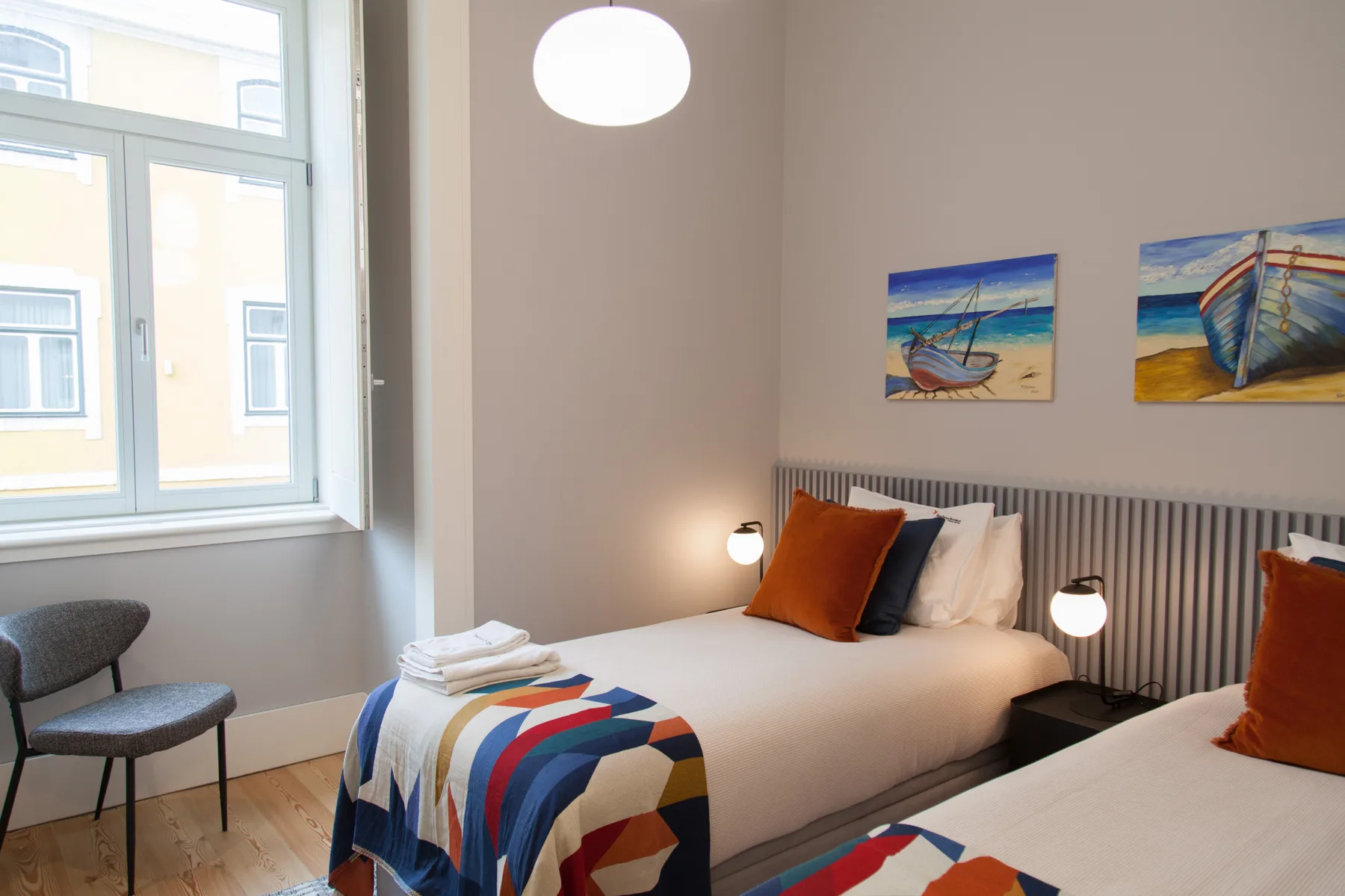 A bedroom with two beds, colorful bedding, and beach-themed wall art.