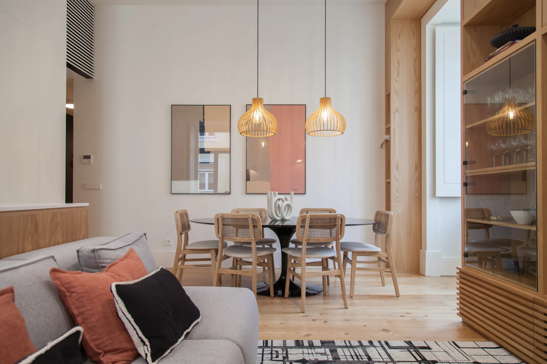 A dining area with a wooden table and chairs beside a living room seating area.