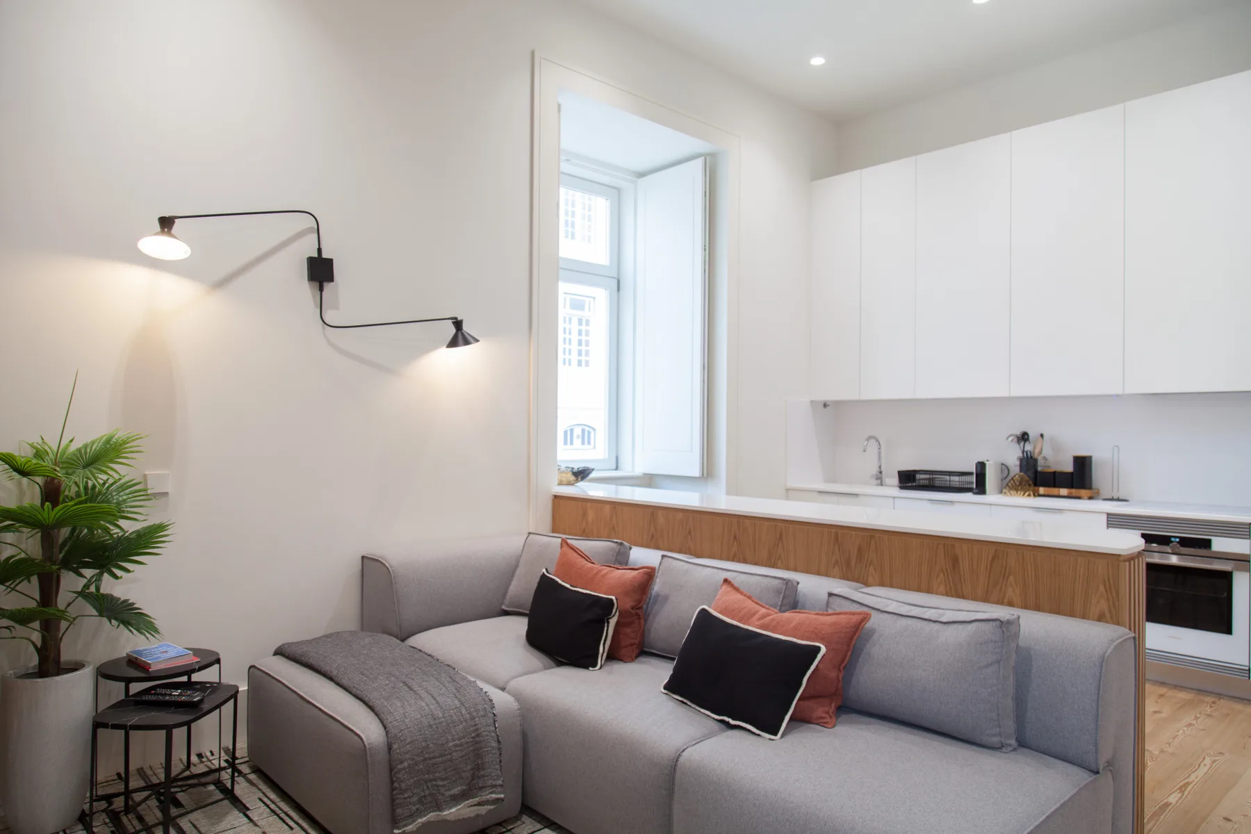 A bright living room with gray seating beside a compact kitchen.
