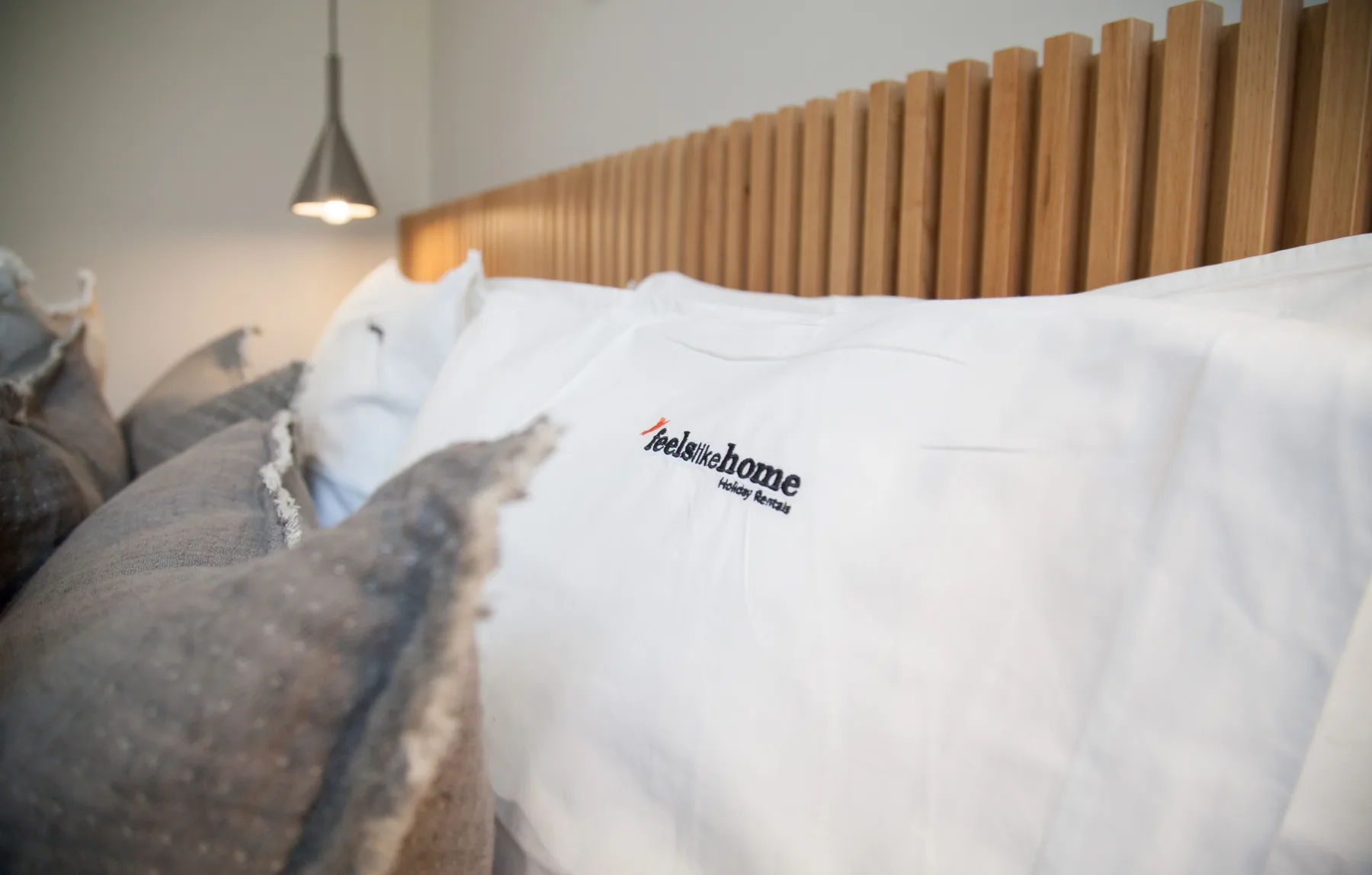 A bedroom close-up shows white pillows against a wooden slat headboard.