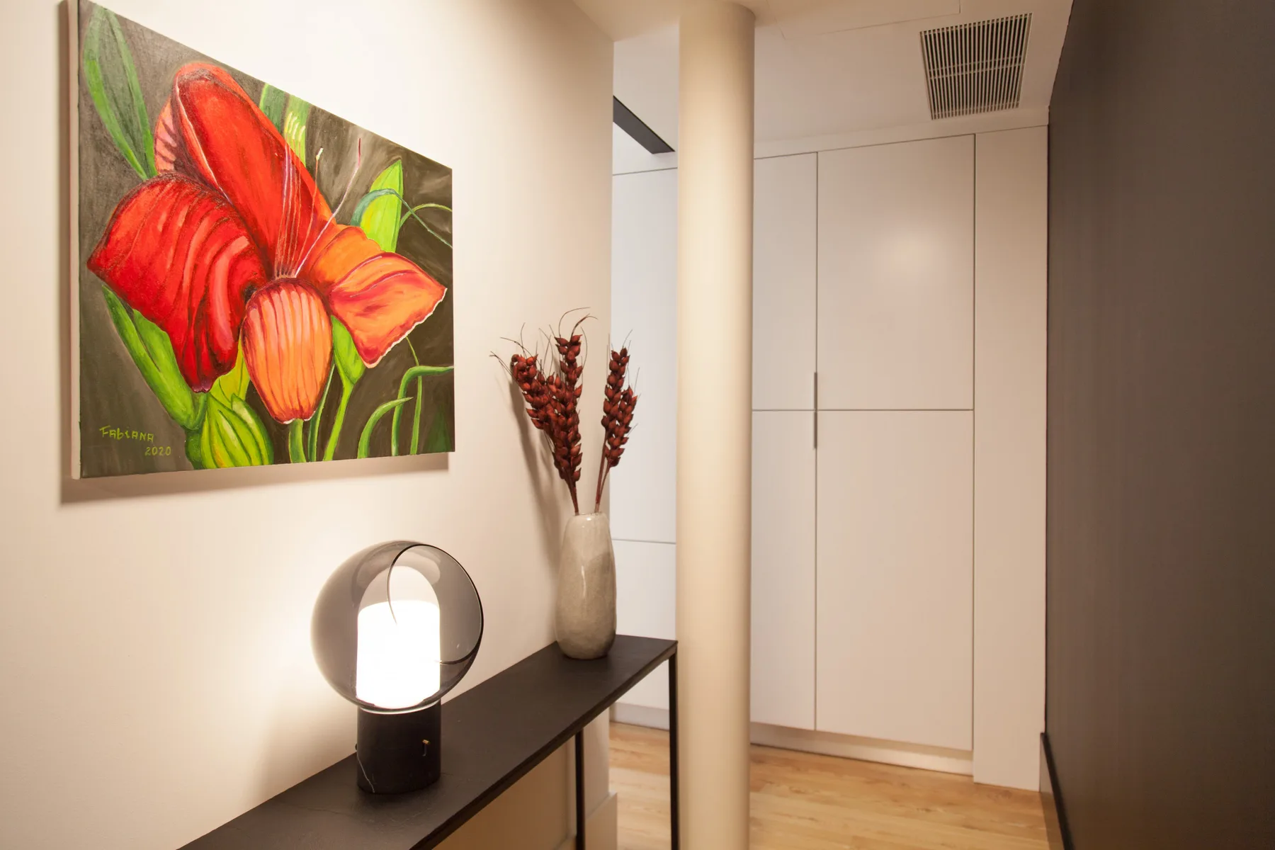 A bright hallway with a colorful flower painting and a narrow console table.