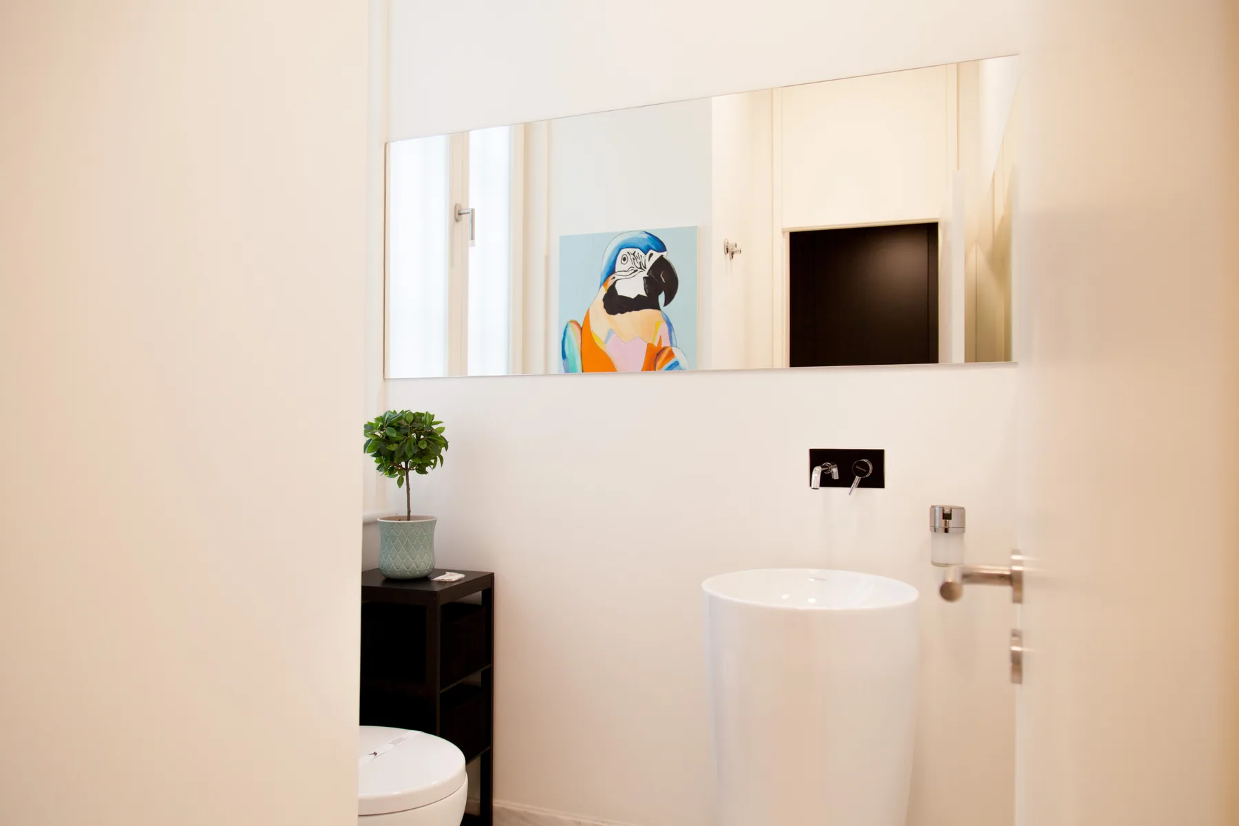 A bright bathroom with a vessel sink, wall mirror, and small potted plant.