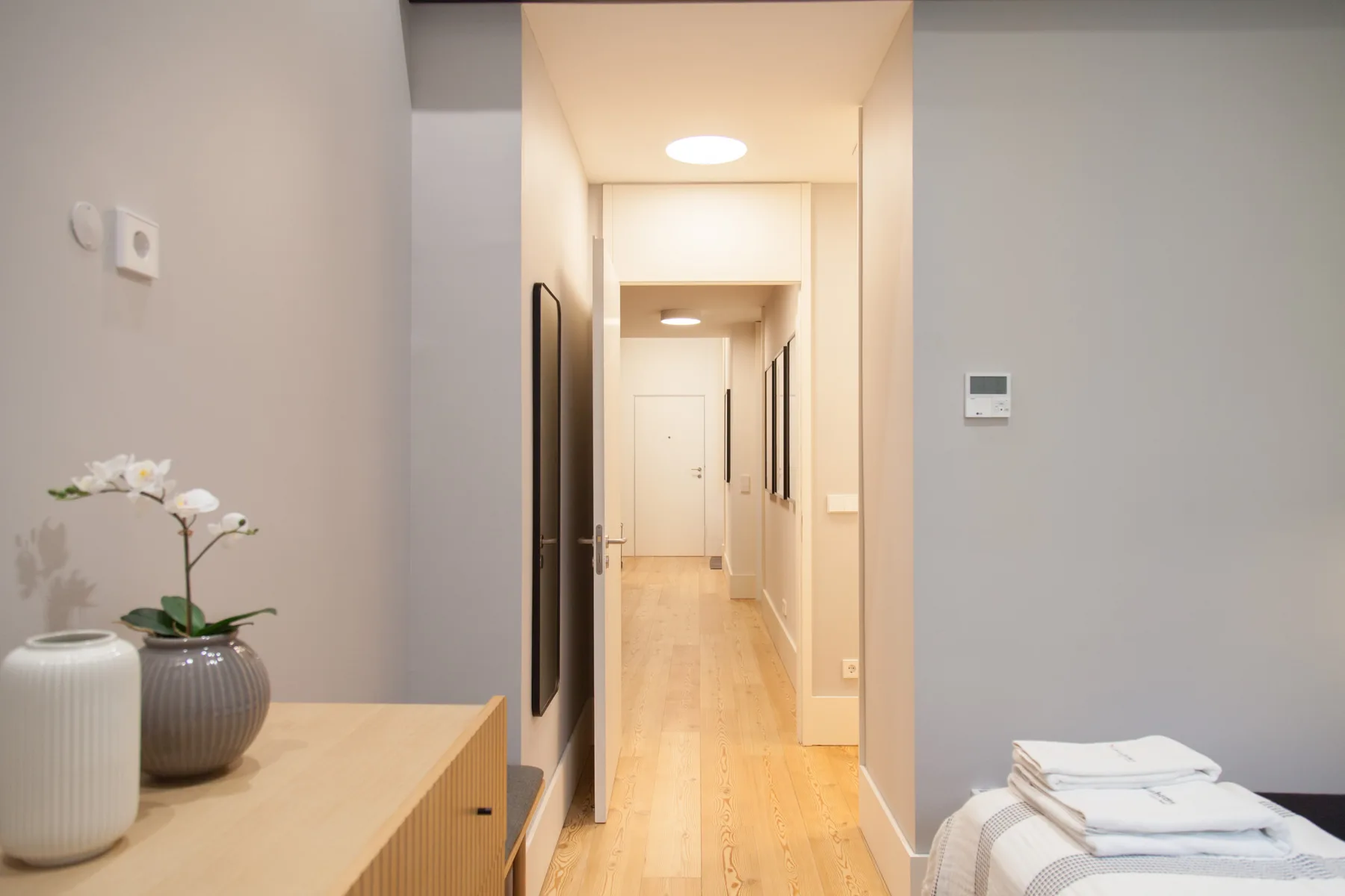 A bright apartment hallway with light wood flooring and a console table.