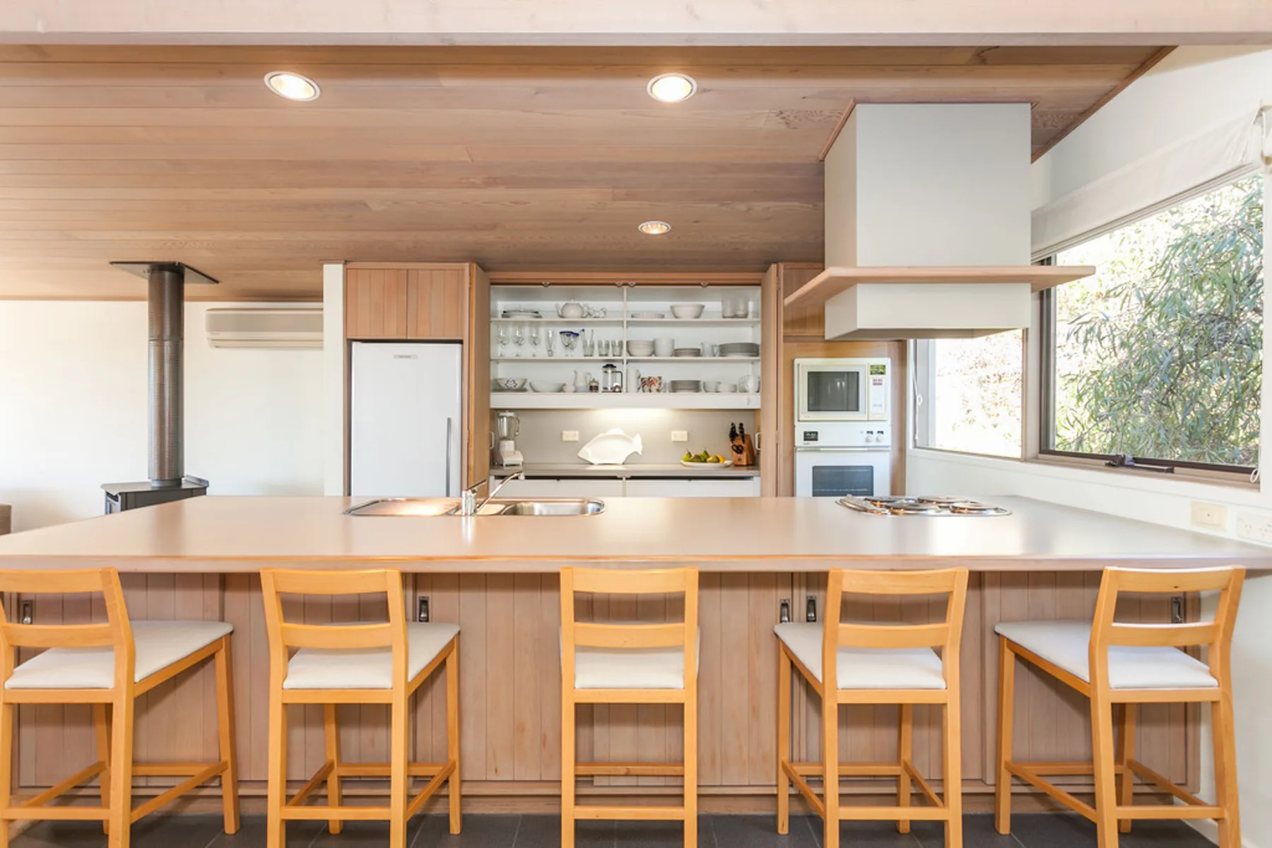 Una cocina luminosa con una isla larga y asientos de madera.