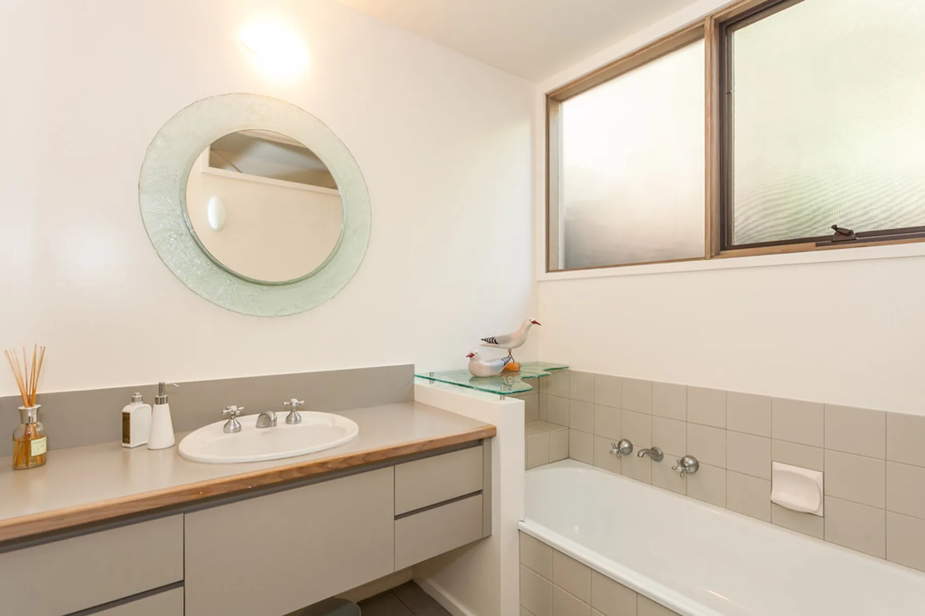 Un lavabo y una bañera están bajo una ventana esmerilada.