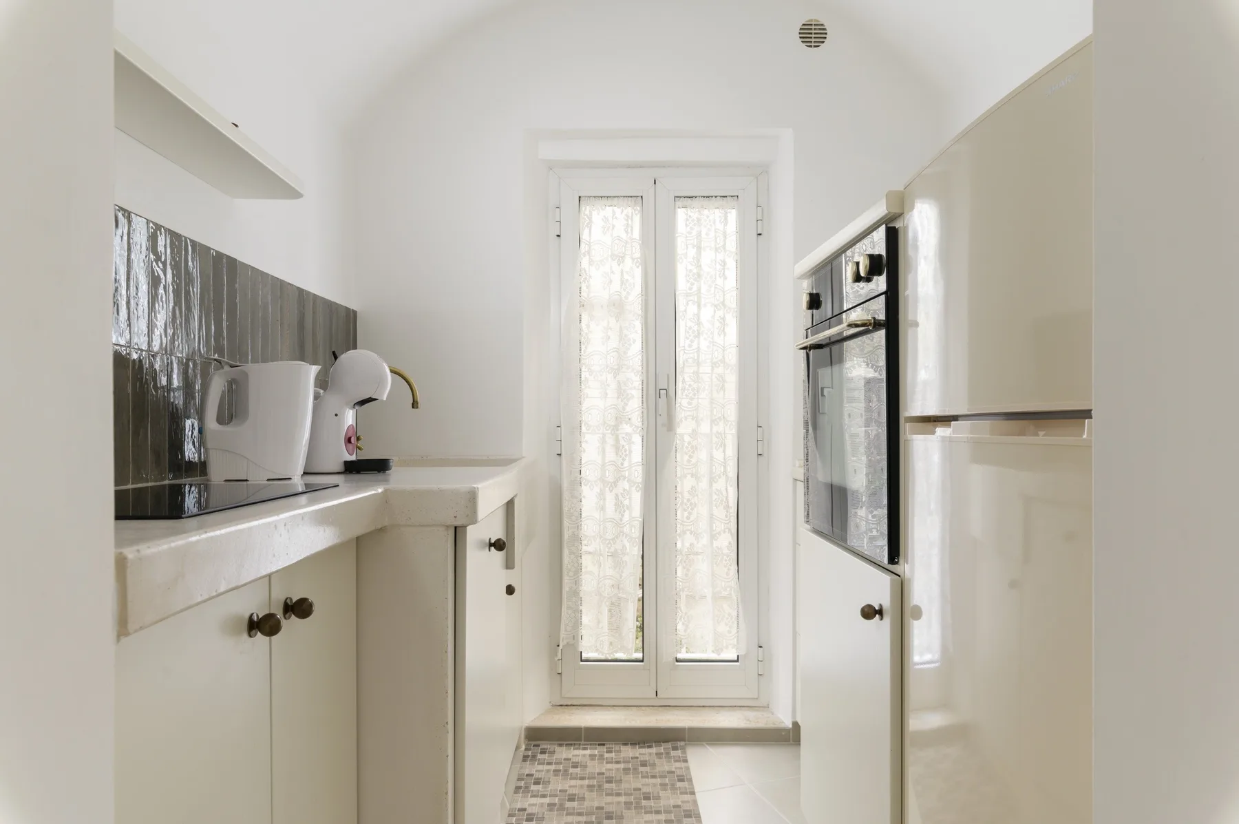 Una cocina galera luminosa con gabinetes blancos y una puerta acristalada al fondo.