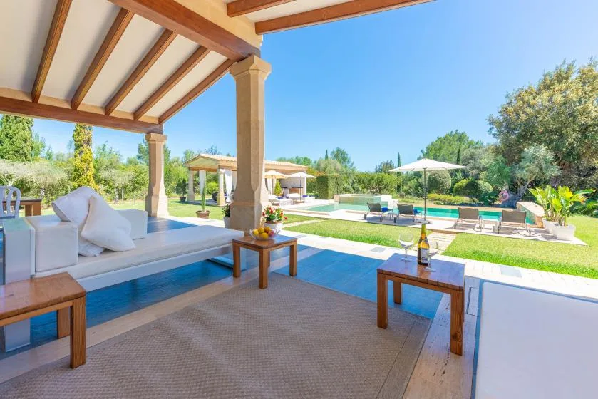 Una zona de estar al aire libre cubierta da a una piscina y un jardín.
