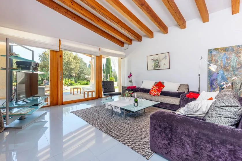 Una sala luminosa con asientos alrededor de una mesa de centro de vidrio y grandes ventanas.
