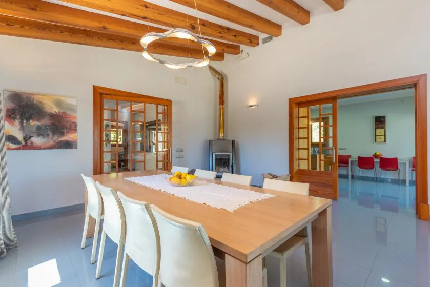 Un comedor con una mesa larga y sillas bajo vigas de madera a la vista.