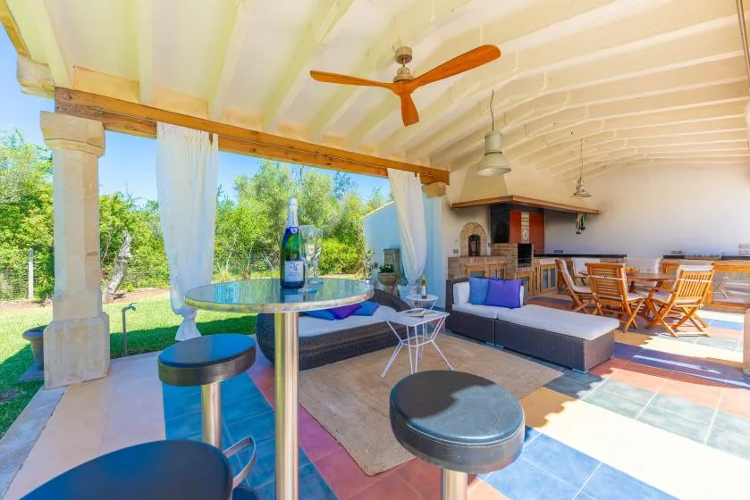 Una sala-comedor abierta con asientos, una mesa y un ventilador de techo.