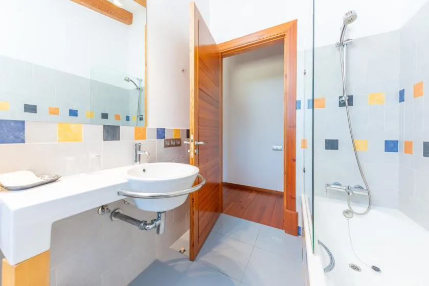 Un baño luminoso con lavabo, encimera y ducha.