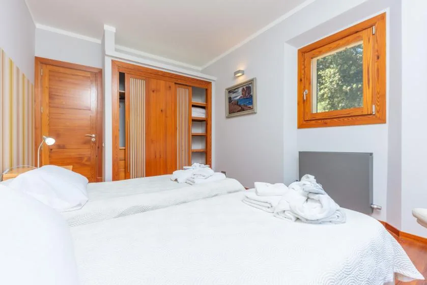 Un dormitorio con ropa de cama blanca, puertas de madera y una ventana.