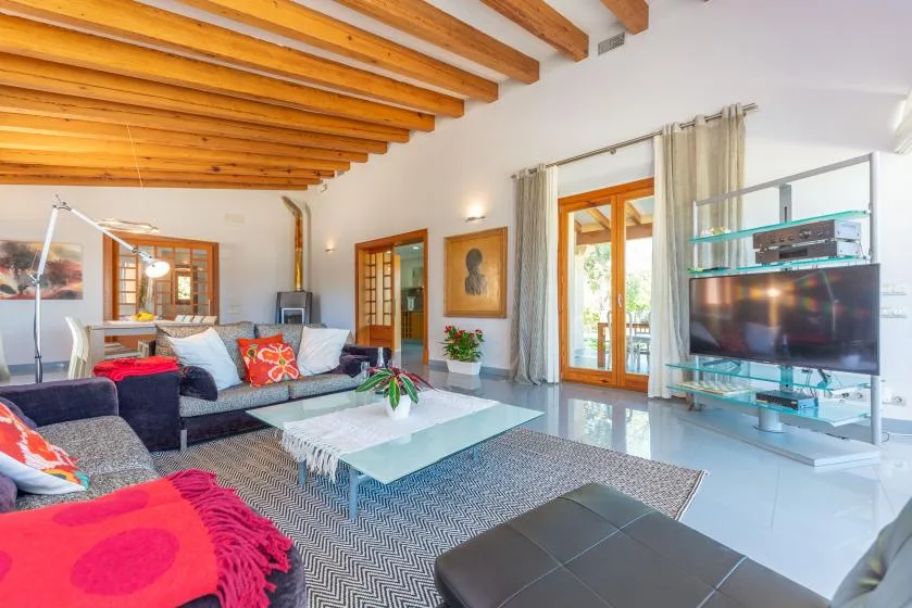 Una sala luminosa con asientos, una mesa de centro de vidrio y ventanas grandes.
