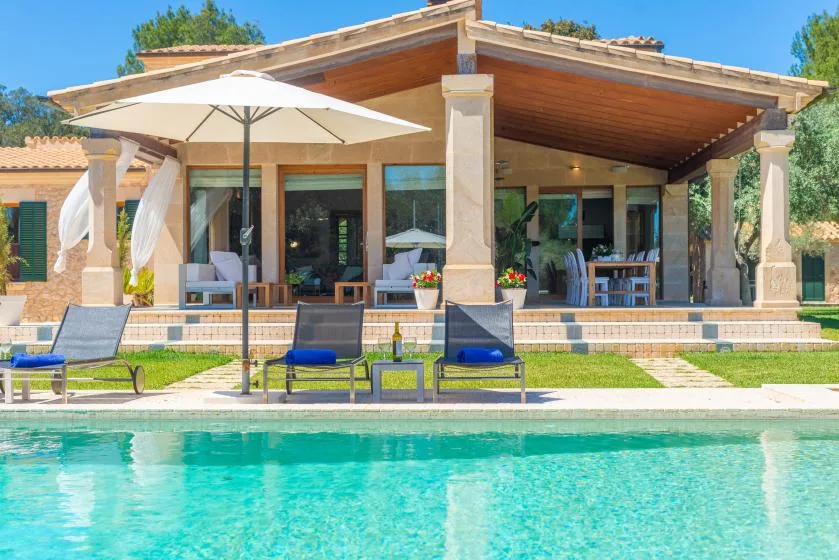 Una piscina y asientos al aire libre están frente a un patio cubierto.