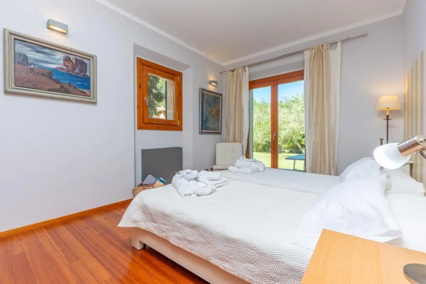 Un dormitorio luminoso con una cama bien hecha y puertas de cristal que dan a la vegetación.