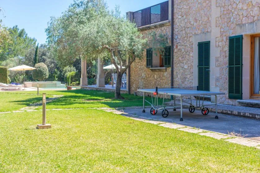 Un patio con césped junto a un edificio de piedra y una mesa de ping-pong.