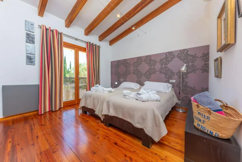 Un dormitorio con una cama doble, una pared estampada y puertas de vidrio hacia un balcón.