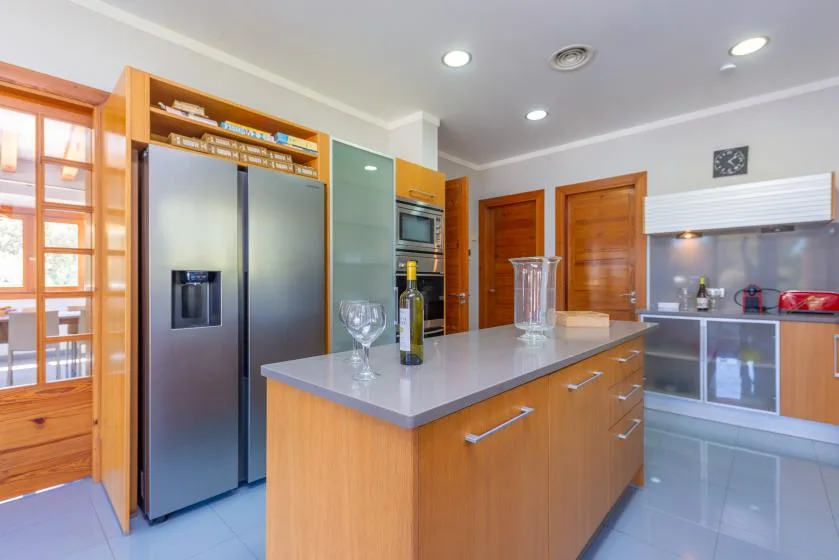 Una cocina luminosa con una isla central y un refrigerador de acero inoxidable.