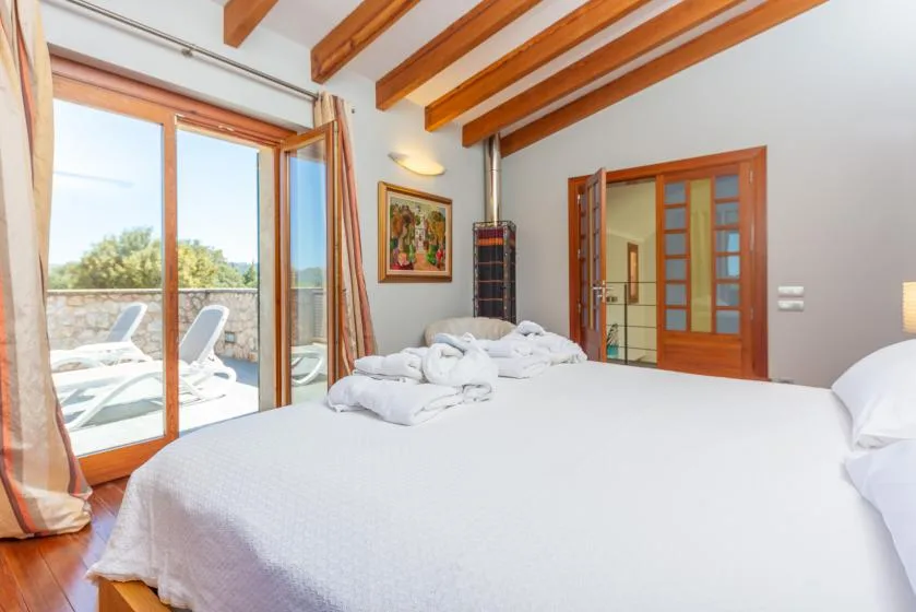 Un dormitorio luminoso con una cama grande y puertas de vidrio que dan a una terraza.