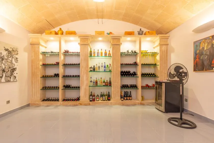 Una bodega con botellas en estantes y un ventilador de pie.
