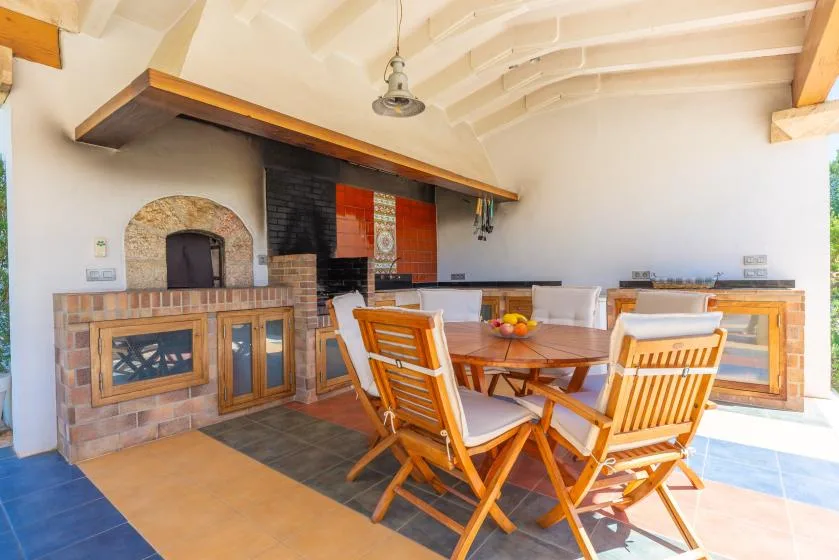Comedor con asientos de madera y una zona de cocción de ladrillo.