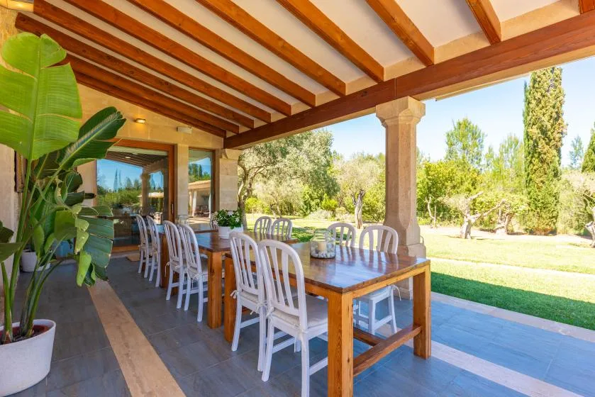 Un comedor en una terraza cubierta con una mesa larga y vistas al jardín.