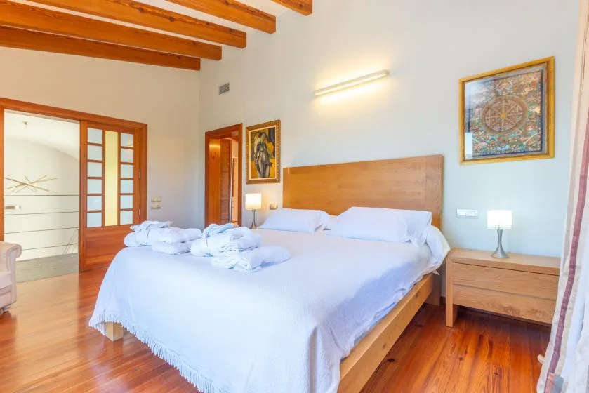Un dormitorio con una cama grande, toallas dobladas y vigas de madera a la vista.