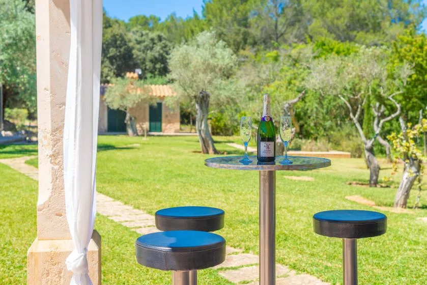 Una zona de asientos en un jardín tiene una mesa redonda pequeña y taburetes sobre el césped.
