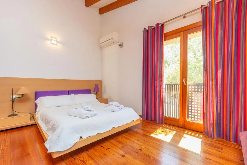 Un dormitorio luminoso con una cama y puertas de vidrio que dan a un balcón.