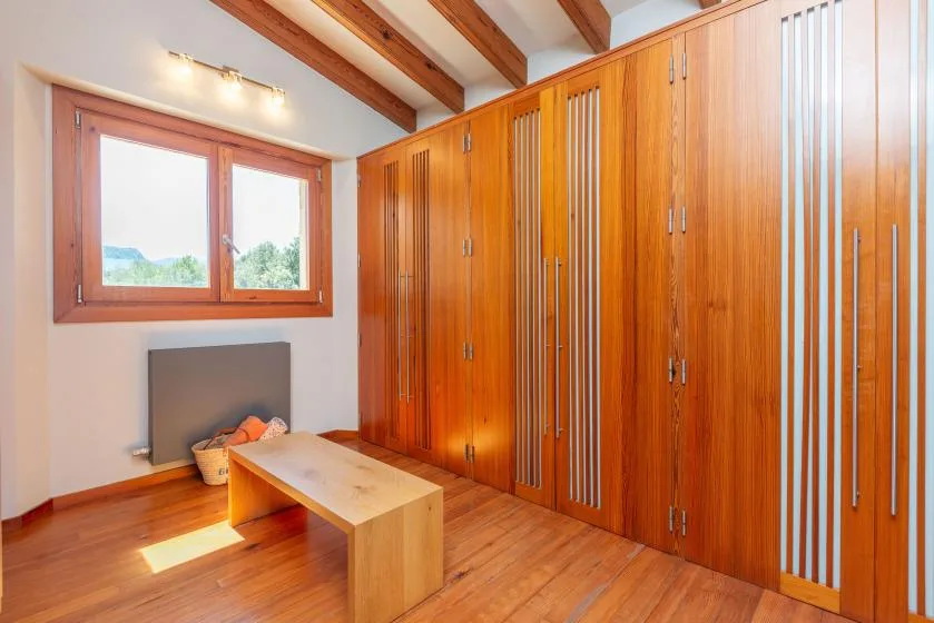 Una habitación revestida de madera con ventana, armarios empotrados y una mesa baja.