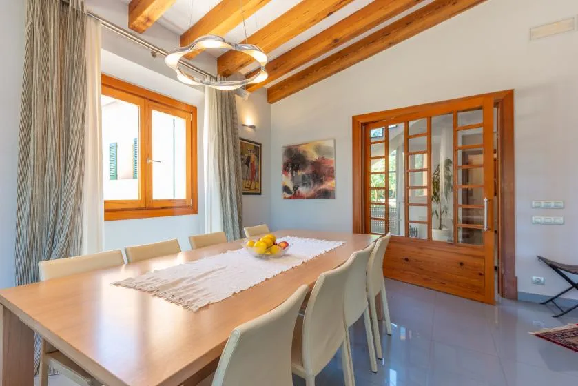 Un comedor con una mesa larga, sillas y vigas de madera expuestas en el techo.