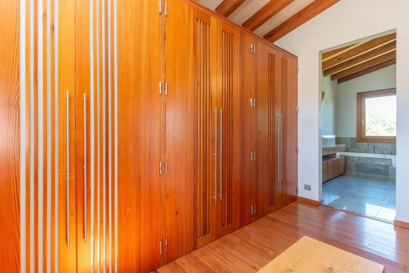 Un pasillo con armarios empotrados de madera y una puerta abierta a un baño.