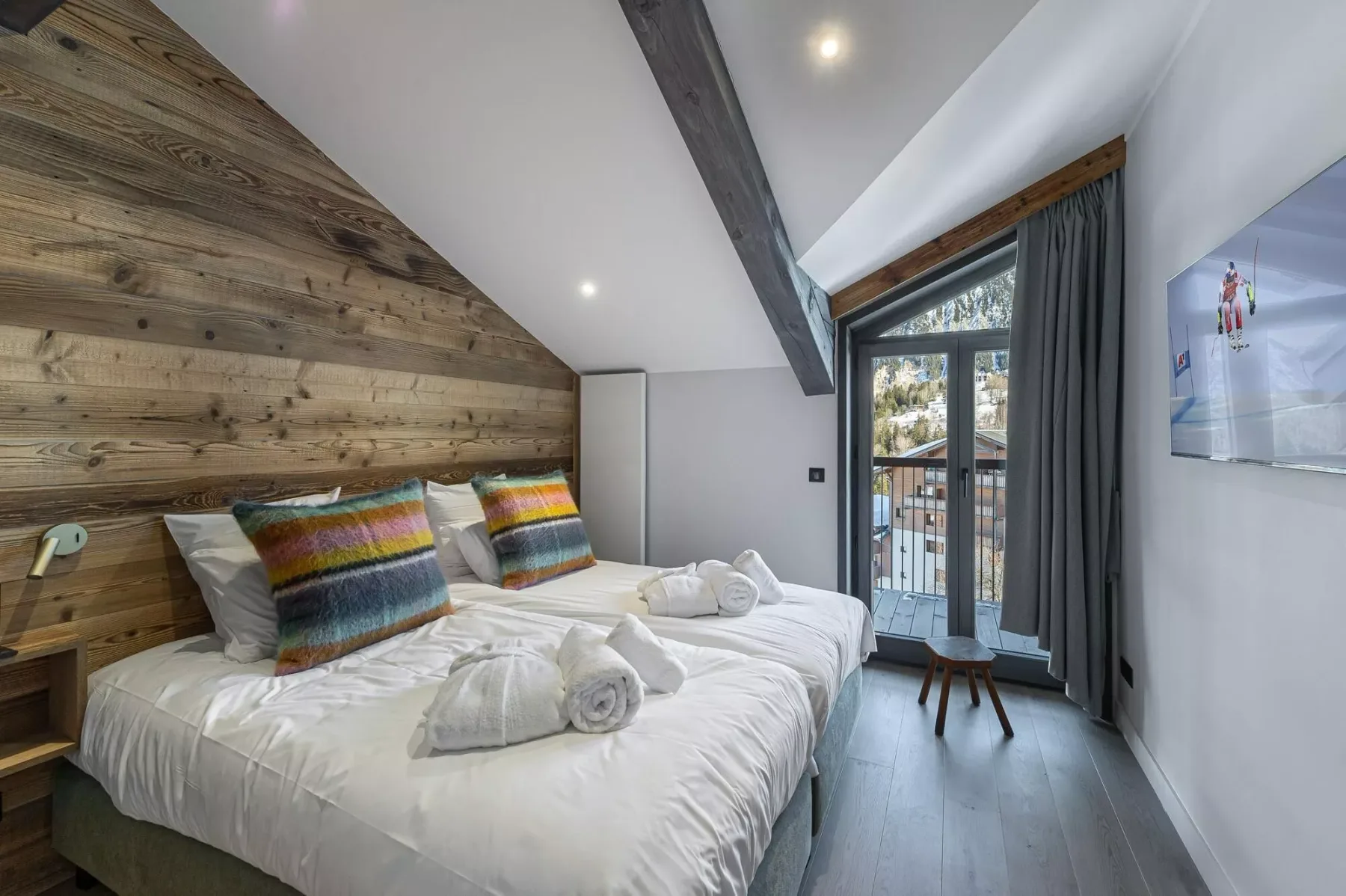 Un dormitorio con una cama grande, almohadas coloridas y una puerta de vidrio que da a un balcón.