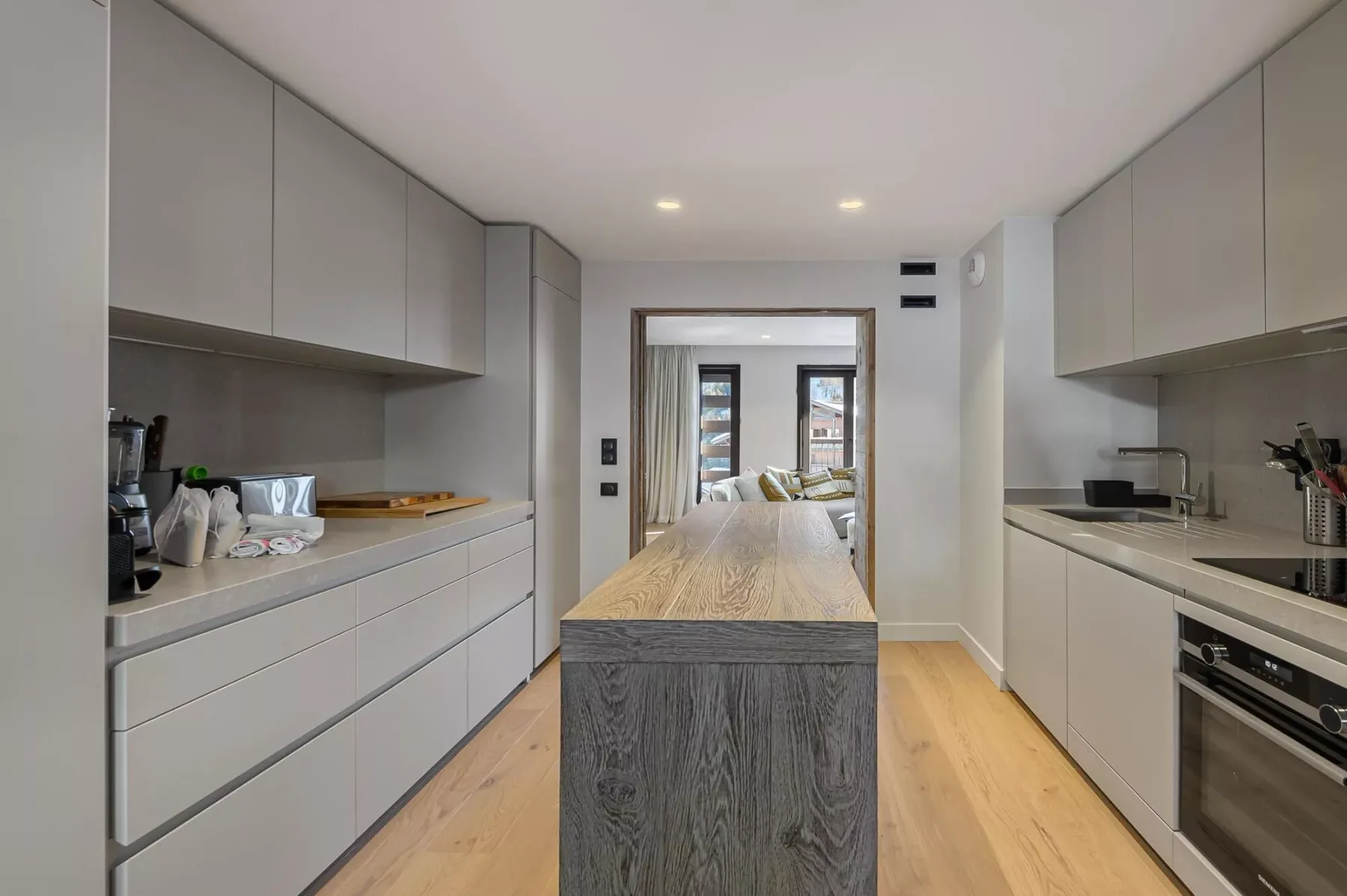 A modern kitchen with a long central island and cabinets along both sides.