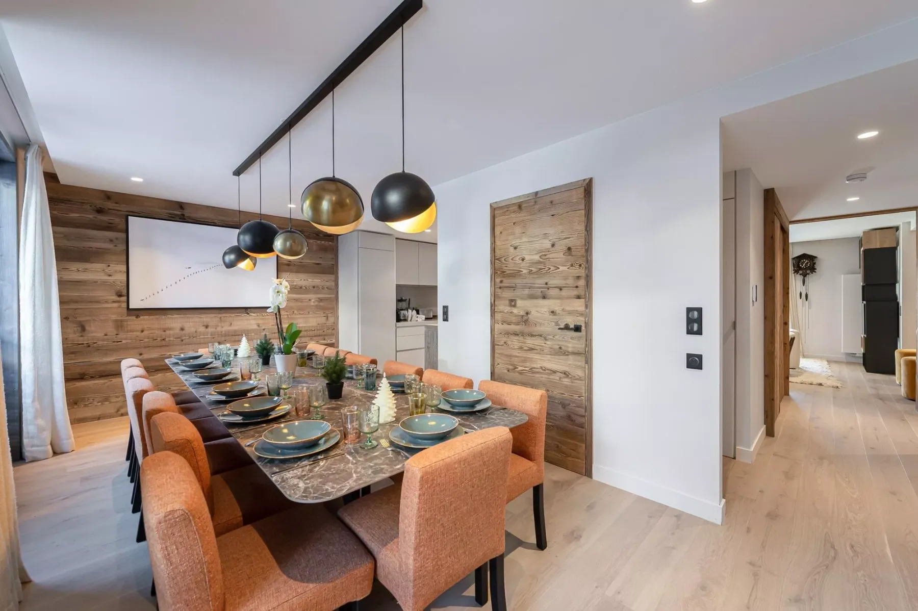 Comedor con una mesa larga, asientos tapizados y lámparas colgantes.