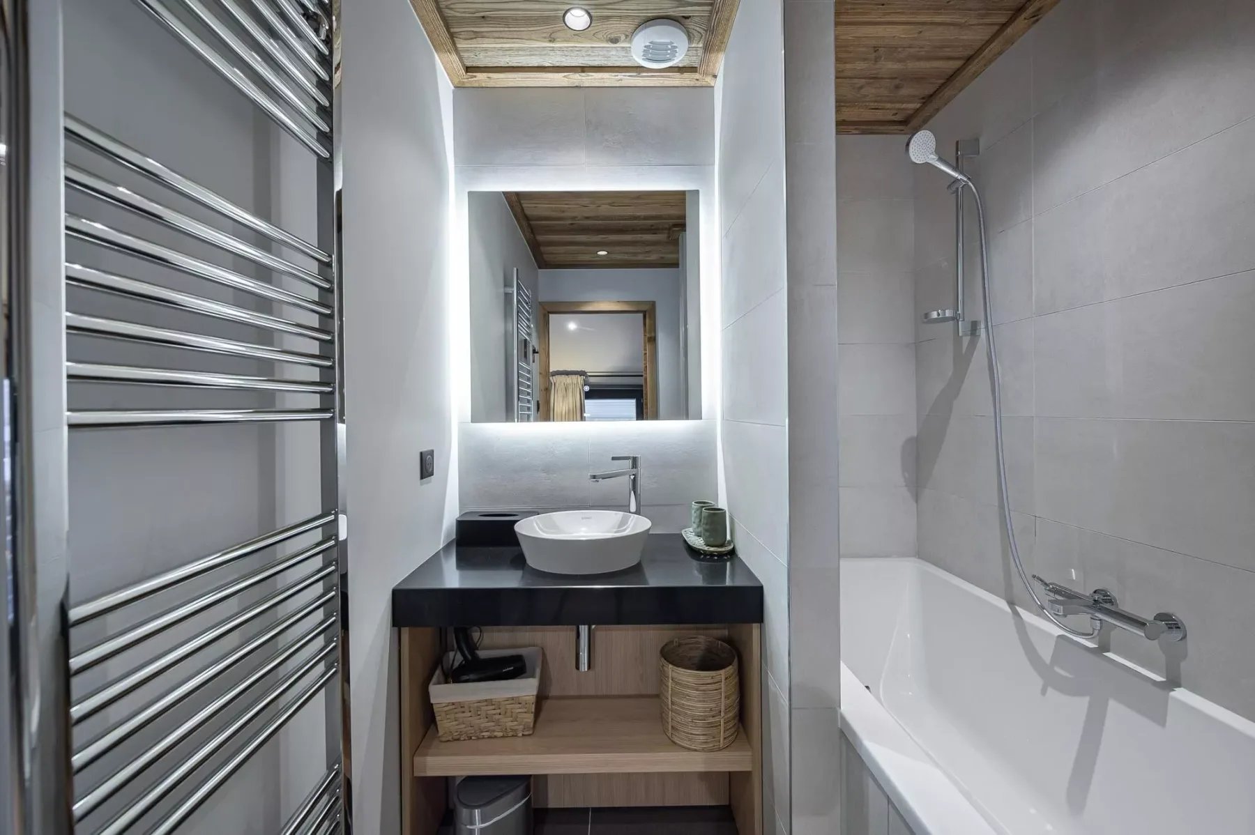 Un baño moderno con lavabo, espejo y bañera con ducha.