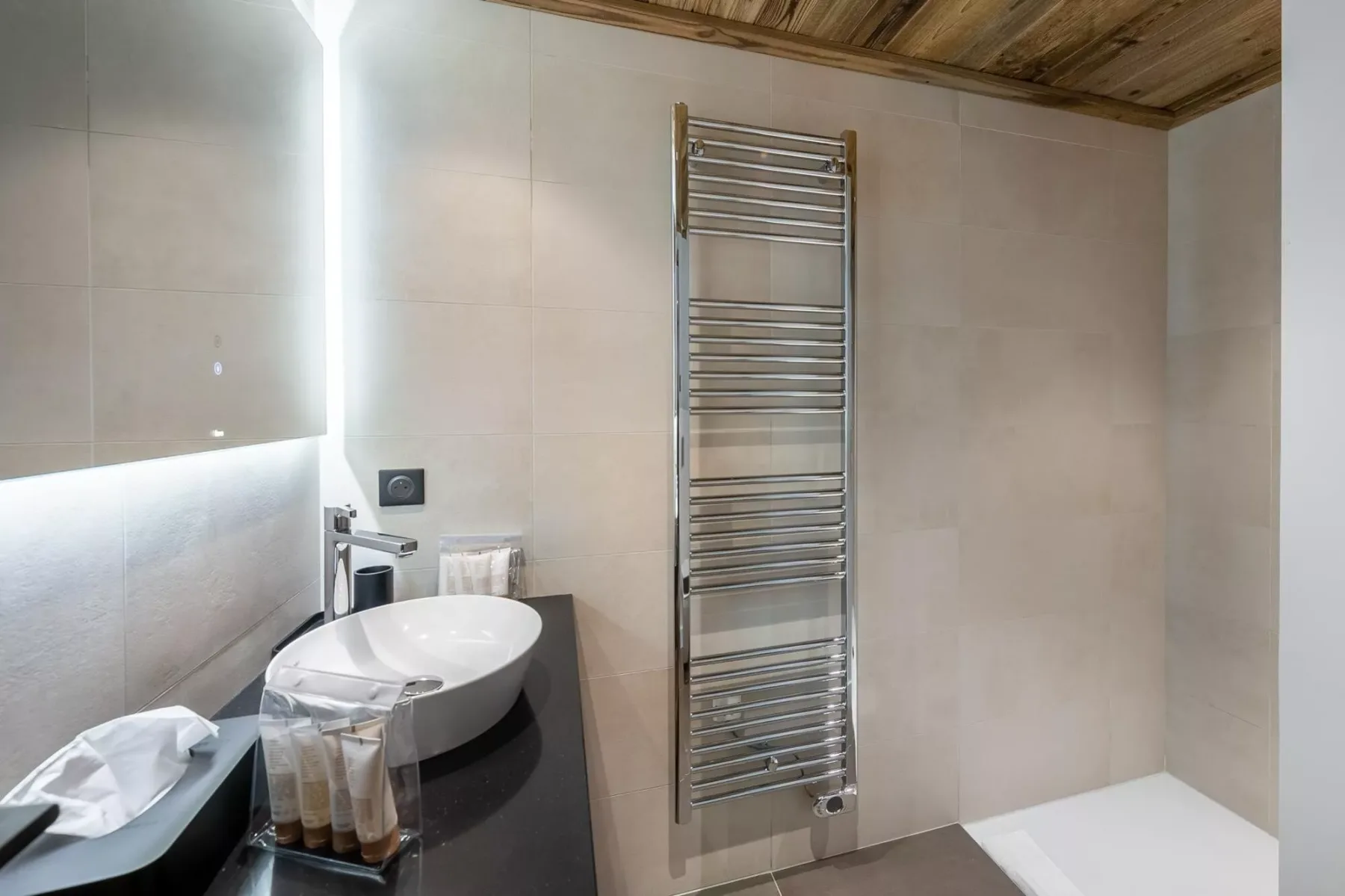 Un baño alicatado con un lavabo sobre encimera y un toallero calefactable.