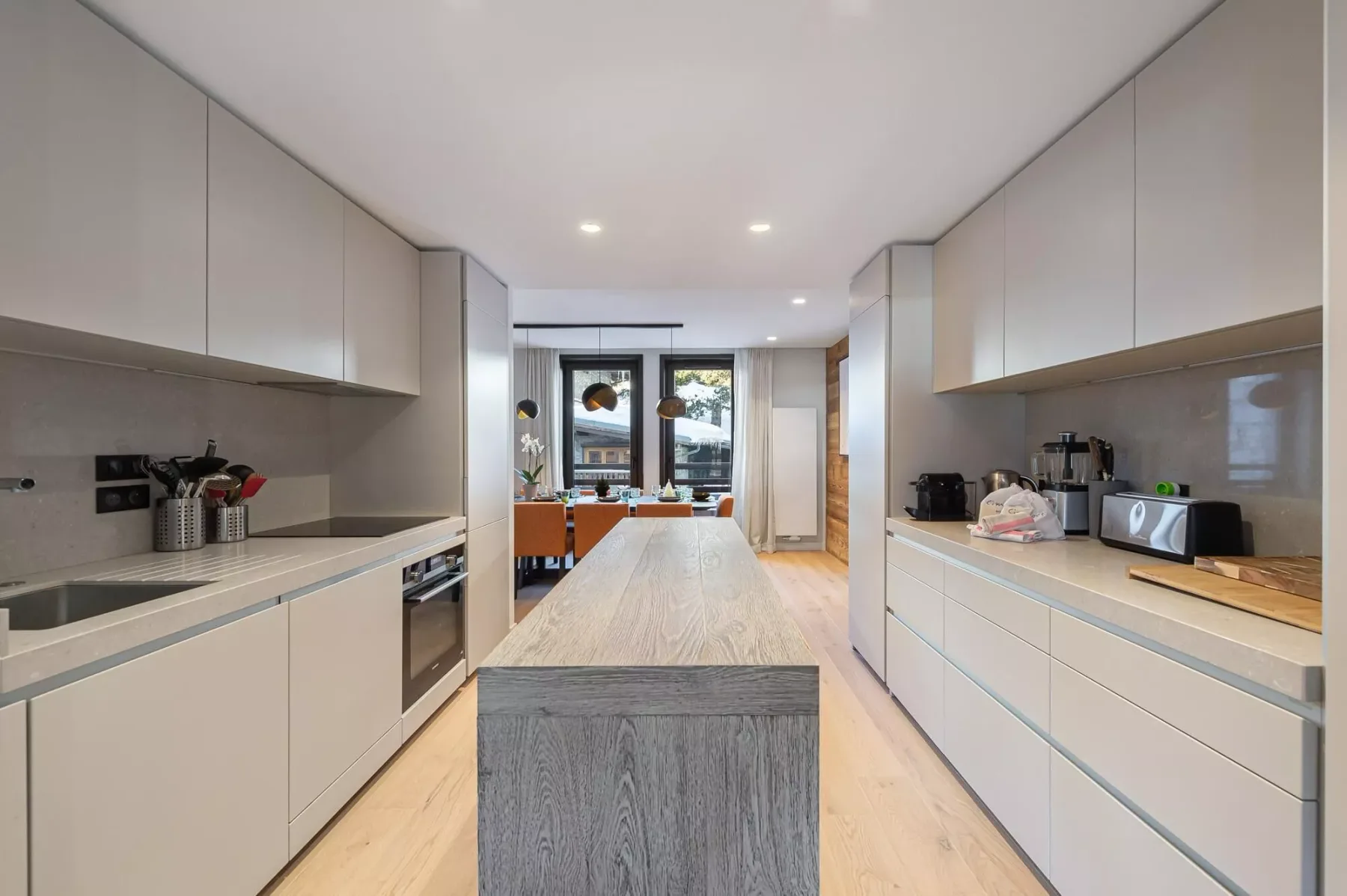 Una cocina moderna alargada con armarios claros y una isla central.