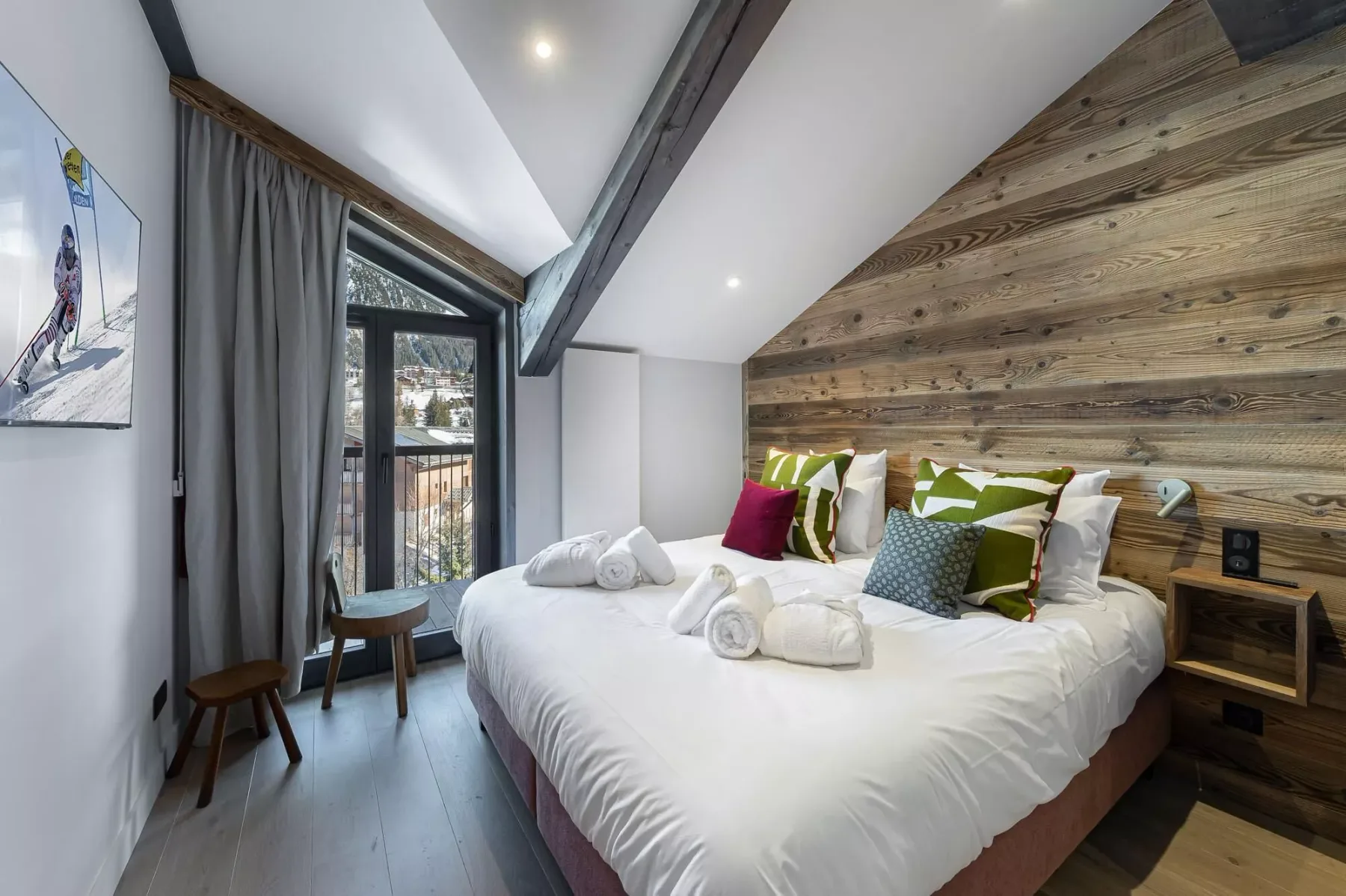 Un dormitorio con una cama grande, una pared revestida de madera y una ventana con cortinas.