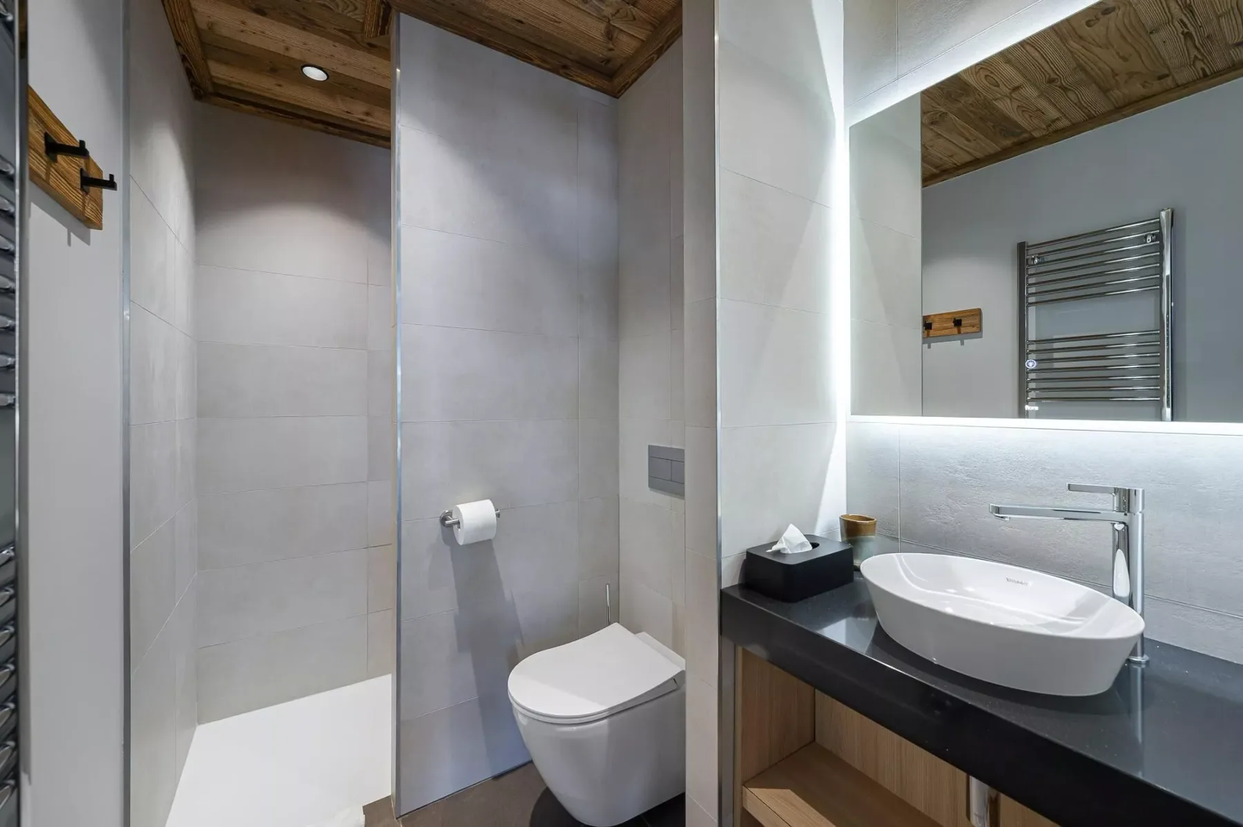 Baño moderno con inodoro, ducha y tocador bajo un techo de madera.