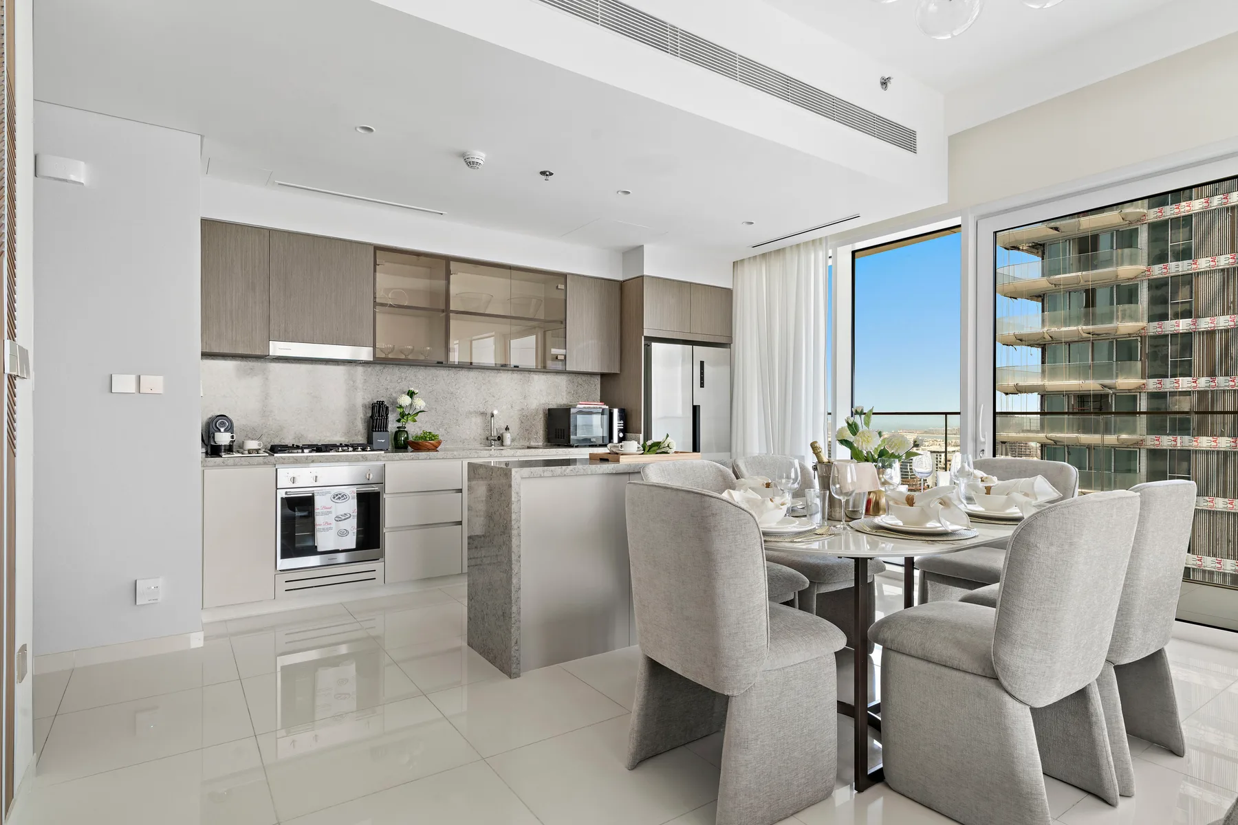 Una luminosa cocina-comedor de planta abierta con una mesa junto a grandes ventanas.